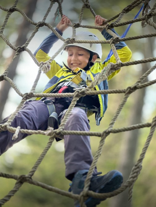 Klettern am Felsen und auf Holzelementen im Klettergarten